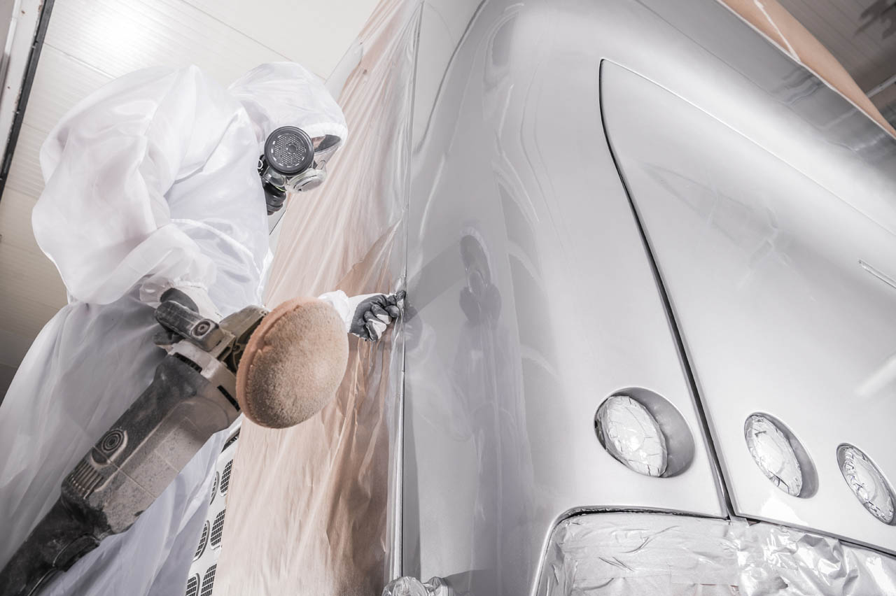 Professionele carrosseriebouwer polijst de nieuw gespoten buscarrosserie Schilderwerk aan de carrosserie